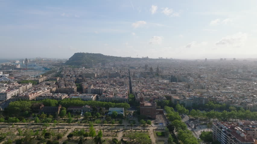 Aerial footage of historic city quarter against sunshine. Town development and famous landmarks, harbour in background. Barcelona, Spain