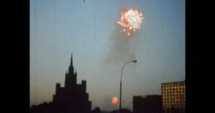 Fireworks on silhouette of night city background. 1980s Moscow, Russia. Holiday celebration in city center. Colorful fireworks on cityscape background. Archival vintage color film. Old retro archive