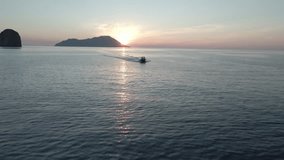 Aerial video of a boat sailing in the sea at sunset on the beaches of the Greek island of Milos