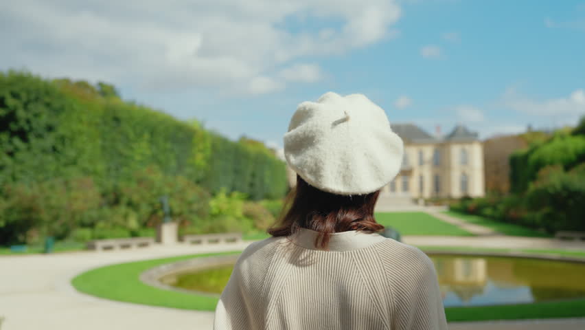 Young girl looking at the manor in the summer garden in Paris