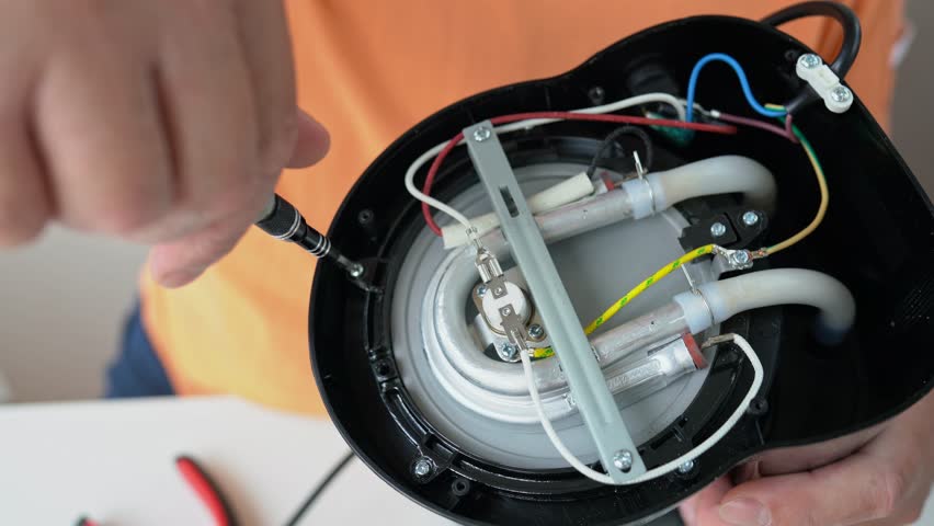 Master hand with screwdriver unscrews detail screwed with a screw of broken home appliance at table in workshop close up. Electronic devices repair service. Professional maintenance coffee maker in 4K - Powered by Shutterstock - Get 15% off with code: PIKWIZARD15