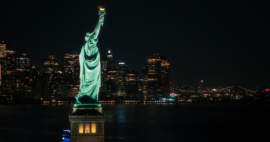 Panoramic Aerial Footage of an American Symbol of Freedom. Cinematic Helicopter Pass by the Statue of Liberty at Night. Landmark New York Monument with Manhattan Skyscrapers in the Background Royalty-Free Stock Footage #1106171151