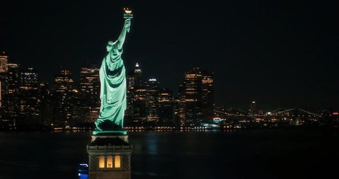 Panoramic Aerial Footage of an American Symbol of Freedom. Cinematic Helicopter Pass by the Statue of Liberty at Night. Landmark New York Monument with Manhattan Skyscrapers in the Background Video de stock