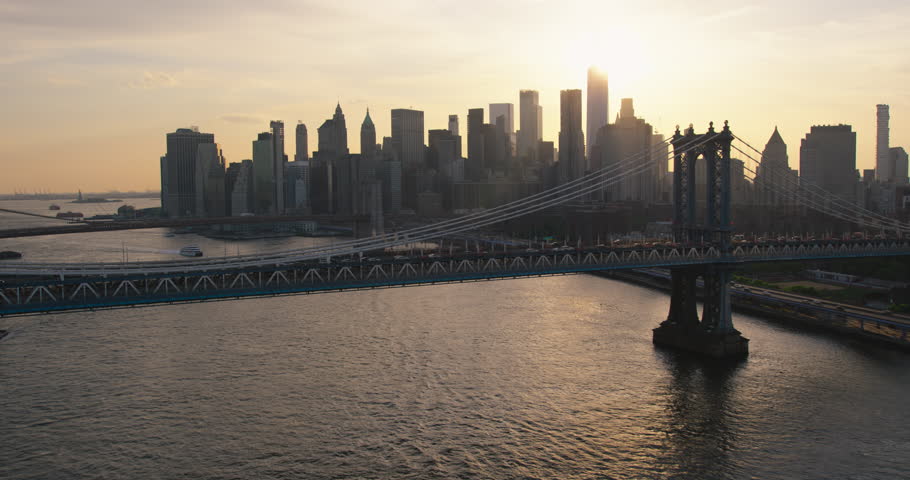 Iconic New York City Landscape Over East River with Skyscrapers, Manhattan and Brooklyn Bridges, Cars and Ferry Boats. Cinematic Evening Urban Skyline with Sunset and Lightly Clouded Sky Royalty-Free Stock Footage #1106171315