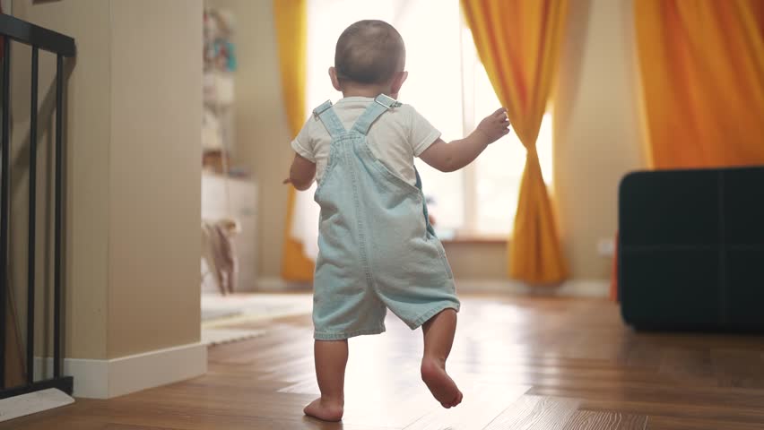 baby first steps. baby goes her father at window learns to walk to take first steps. happy family kid dream concept. dad calls son baby first steps indoors. happy family indoors concept lifestyle Royalty-Free Stock Footage #1106172131