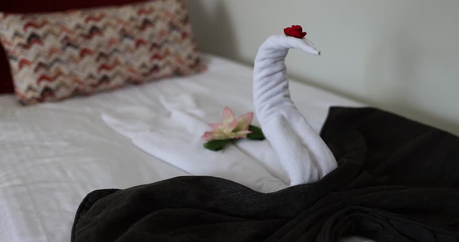 Toallas de cisne en la cama en una habitación de hotel