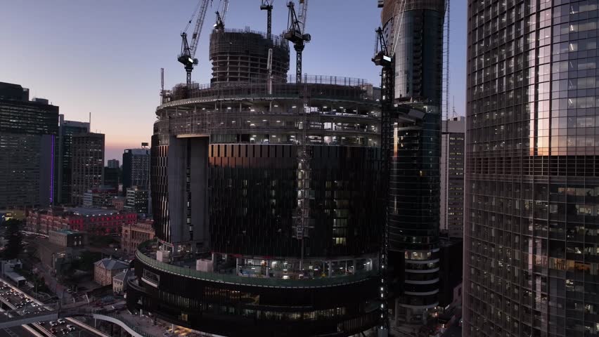 Drone orbiting shot of Brisbane's Queens Wharf Casino development. Shot from above Brisbane River heavy traffic on the Riverside Motorway. Shot at Sunset, with 1 William St Skyscraper in foreground Royalty-Free Stock Footage #1106175161