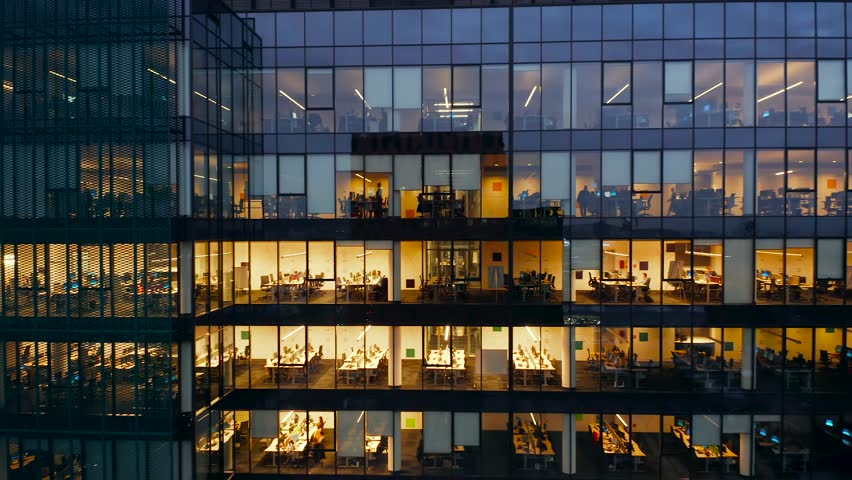 Aerial View Windows Office Buildings Illuminated at Night. Glass Architecture, Corporate Building at Night. Cinematic Shot of the Corporate Building with Employees Working Their Asses Off. Royalty-Free Stock Footage #1106177901