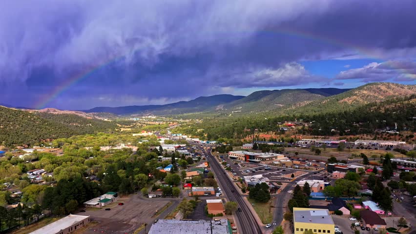 Rainbow over a city surrounded by vegetation and mountains. Ruidoso, New Mexico. Drone aerial shot.