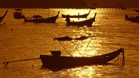 Beautiful sunrise above fishing boats It creates a beautiful reflection in the water surface,Scenic reflection of beautiful sunshine in the sea fishing boats are floating in the sea of Phuket Thailand