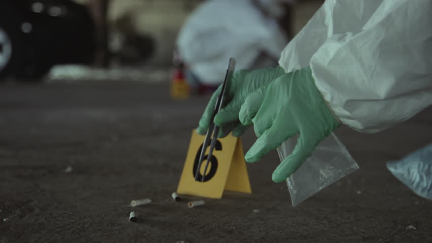 Close-up handheld shot of hands of unrecognizable forensic expert in protective suit and gloves gathering cigarette butts from ground using forceps, putting into ziplock bag, sealing it and leaving Royalty-Free Stock Footage #1106199471