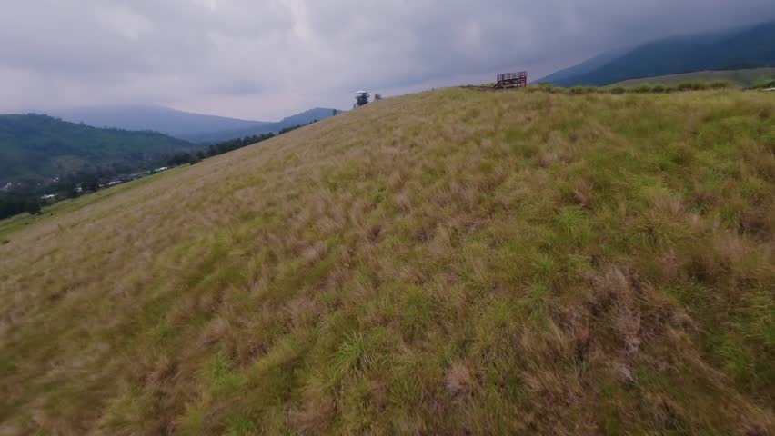 Mountain autumn ridge near sightseeing observation tower at hilly terrain road trail. FPV drone low dynamic shot extreme sport motorcycle travel adventure picturesque parking chilling rocky cloudy sky
