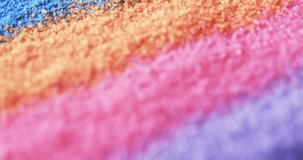 Video of close up of rainbow coloured sand grains and copy space background. Sand, texture and pattern concept.