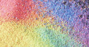 Video of close up of rainbow coloured sand grains and copy space background. Sand, texture and pattern concept.