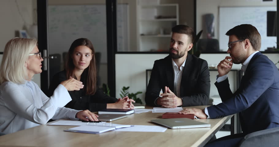 Serious older mature business woman speaking to listening, nodding colleagues at office meeting table, offering decision, idea for project, telling strategy. Diverse team discussing tasks Royalty-Free Stock Footage #1106206017