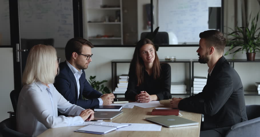 Serious confident young business partners talking on team meeting, negotiating on deal, contract, getting happy, positive, shaking hands over table. Employer hiring candidate after job interview Royalty-Free Stock Footage #1106206051