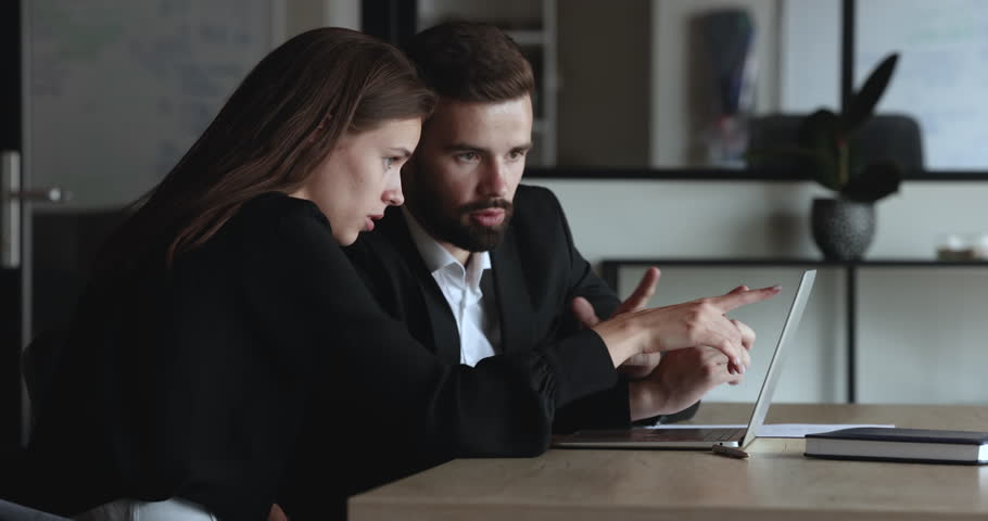 Couple of focused excited young business colleagues watching online content on laptop together, pointing at screen, getting happy, cheerful, laughing, talking, discussing Internet presentation Royalty-Free Stock Footage #1106206059