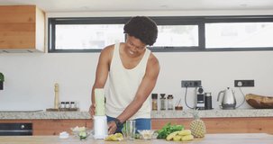 Animation of vegan food text over african american man making vegetable smoothie. Vegan food, organic fresh food, and sustainability concept digitally generated video.
