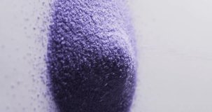 Vertical video of close up of heap of purple sand grains and copy space on white background. Sand, texture and pattern concept.