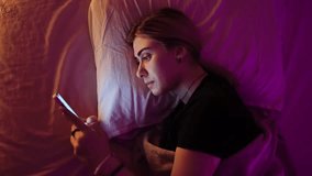 A Woman Typing on Smartphone Lying in Bed at Night. Writing a Message Online, Social Networks, Gadgets - Powered by Shutterstock - Get 15% off with code: PIKWIZARD15