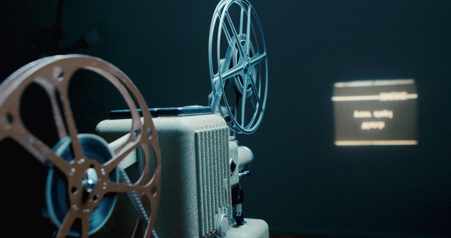 Vintage 8mm Film Projector Runs Film and Projects it Onto a Wall in a Room. Old Home Movie Projector Working and Projecting a Movie Onto a Screen with a Visible Beam of Light 
