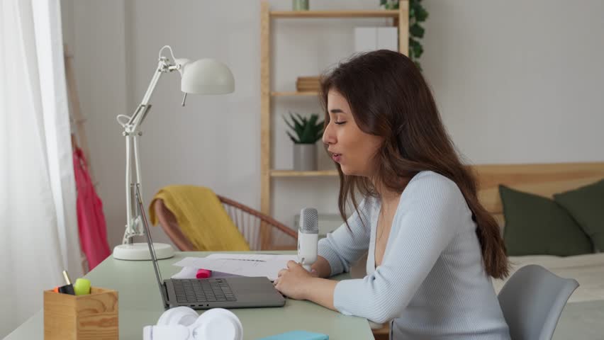 Woman recording a podcast with microphone and laptop.