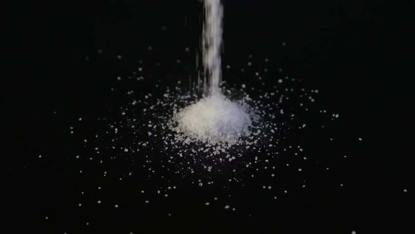 Aspartame powder falls on black surface. Food additive E951. Aspartame is an artificial non-saccharide sweetener 200 times sweeter than sucrose, used as sugar substitute in foods and beverages. Royalty-Free Stock Footage #1106214601