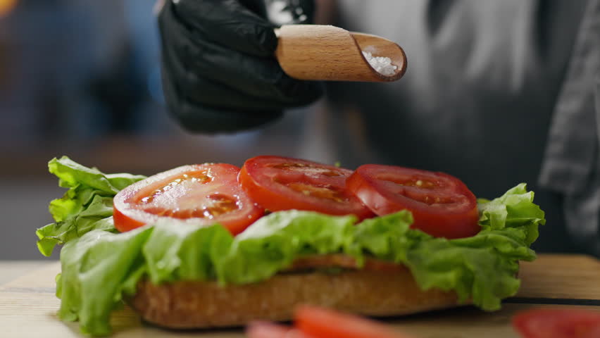 Bacon, a professional chef cooks confidently Salt vegetables cooking process in a street bakery. stable camera movement responsible chef takes orders prepares sandwiches adding salt vegetable bacon Royalty-Free Stock Footage #1106215459