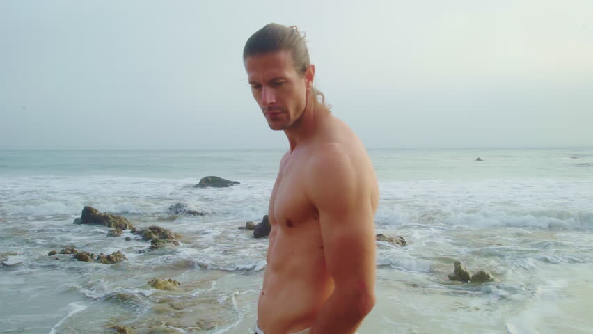Handsome man shirtless posing near Pacific ocean. Male portrait on evening beach Royalty-Free Stock Footage #1106217015