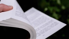 Girl Flipping through the Pages of an Open Book in Nature in Rays of Sunlight. Close up. Slow motion. Hands turn pages. Blurred nature background. Concept education, science, resting. Copy space. - Powered by Shutterstock - Get 15% off with code: PIKWIZARD15