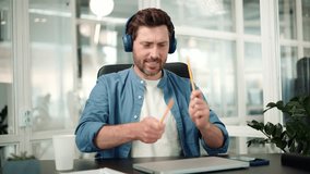 Happy funny business man in blue headphones dancing at workplace celebrating good news pretend playing drums with pencils having fun enjoying work break listen music singing song at office. - Powered by Shutterstock - Get 15% off with code: PIKWIZARD15