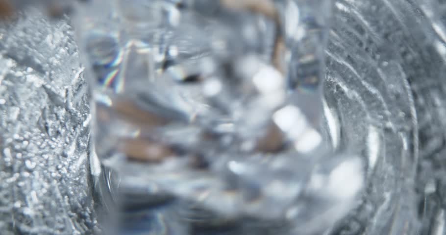 Ice cubes rotating in a glass with crystal clear water.