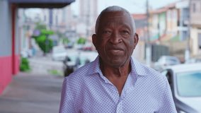 Portrait of a happy black senior Brazilian man standing in street sidewalk looking at camera with smiling expression. Elderly African American male with joyful emotion in urban setting - Powered by Shutterstock - Get 15% off with code: PIKWIZARD15