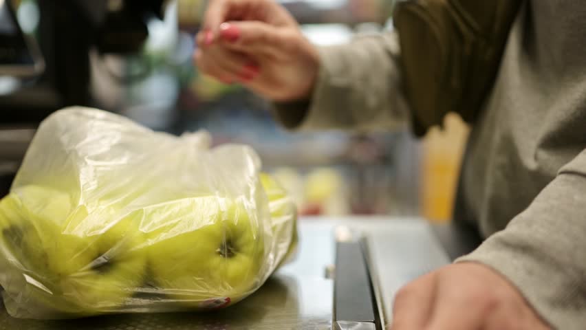 girl Waights a plastic bag with a apples on a self-service checkout Royalty-Free Stock Footage #1106233739