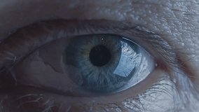 Extreme close-up of human eye. Watching concept. Watcher, observer. Blue iris. Loop, looping video. Wrinkled skin. Reflection in the eye. Cinematic video. Slow motion. Soft light. Cold color.