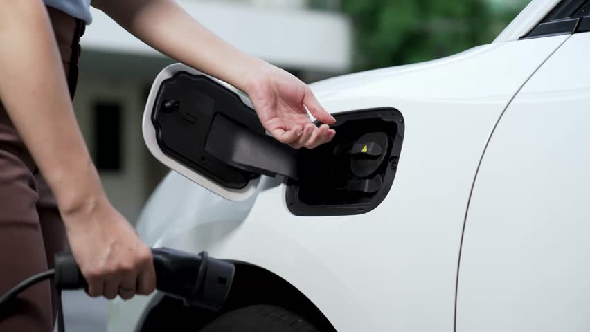 Woman recharge her electric car with EV charger from smart home charging station display futuristic digital battery status hologram. EV car and home energy infrastructure for sustainable power. Peruse Royalty-Free Stock Footage #1106246447
