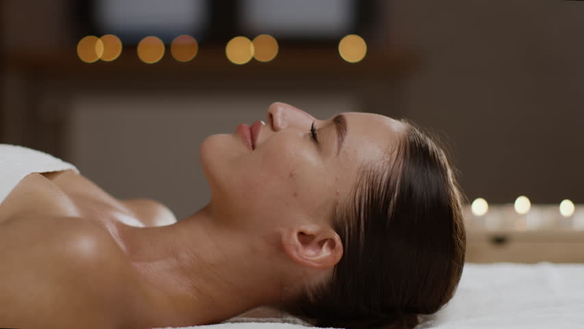 Professional body care. Young beautiful lady getting relaxing facial massage at spa, professional masseur hands massaging face skin, side view portrait, slow motion Royalty-Free Stock Footage #1106248697