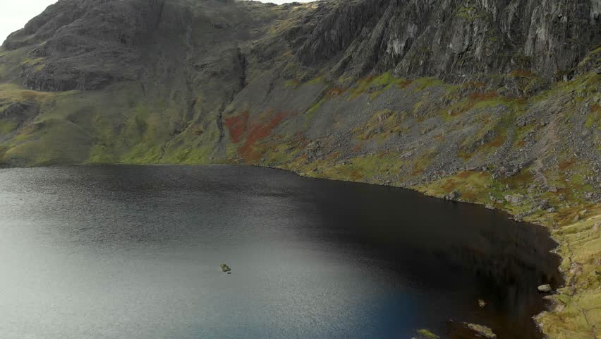 Aerial view of Stickle Tarn lake, located in the Lake District, Cumbria, UK. Popular tourist attractions in Great Langdale valley, famous for its glacial ribbon lakes and rugged mountains.