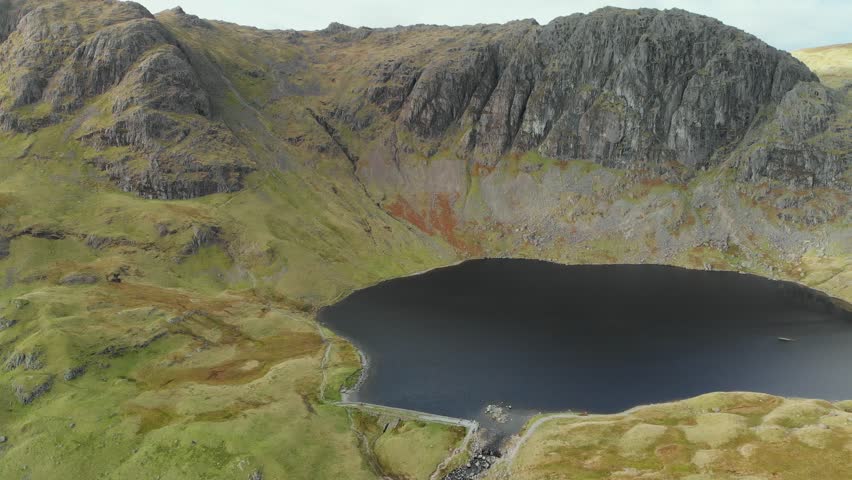 Aerial view of Stickle Tarn lake, located in the Lake District, Cumbria, UK. Popular tourist attractions in Great Langdale valley, famous for its glacial ribbon lakes and rugged mountains.