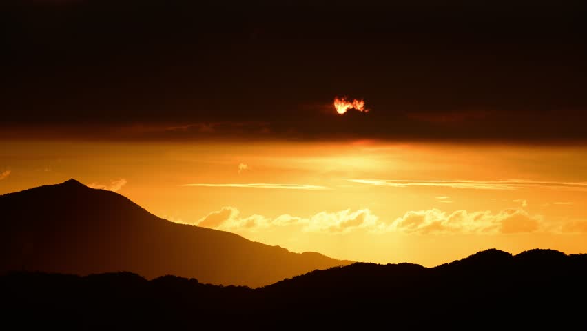 The orange-red sun emerged from the clouds and moved toward the horizon. View of the urban landscape from Dajianshan Mountain, New Taipei City, Taiwan