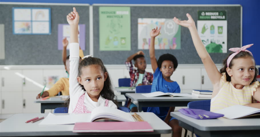 Happy diverse schoolchildren at desks raising hands in classroom at elementary school. School, learning and education, unaltered. Royalty-Free Stock Footage #1106260715
