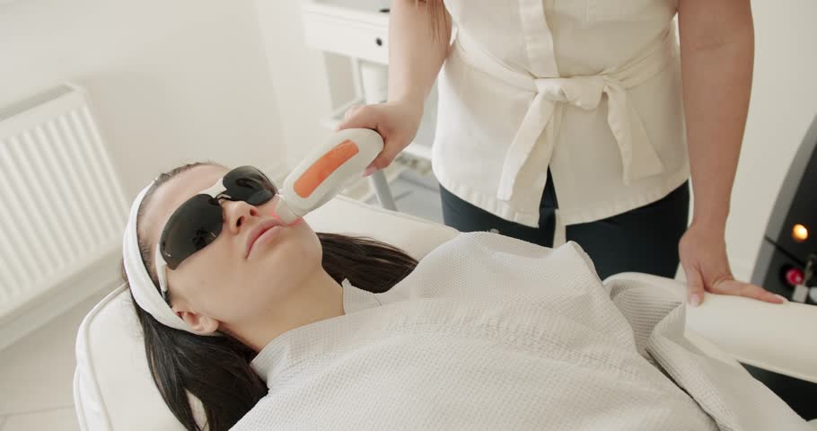 Beauty woman with protective glasses, aesthetic medicine is performing procedure. Beautician cosmetologist doing procedure fractional microneedle mesotherapy rejuvenation with laser technology. Royalty-Free Stock Footage #1106267397