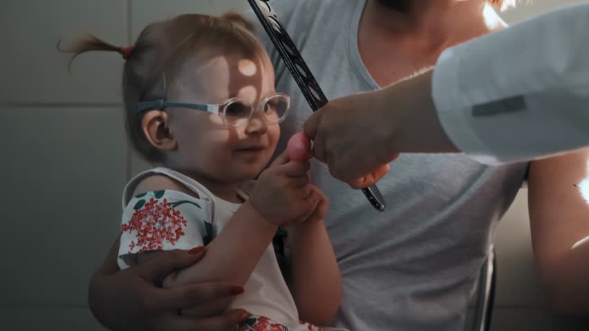Diagnostic procedure skiascopy with pediatric ophthalmologist. Optometrist illuminates pupil of eye with mirror of ophthalmoscope, skiascopic ruler. Checking vision of little girl kid with eye disease Royalty-Free Stock Footage #1106269223