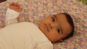 Sweet newborn baby girl in bed. Video of happy and joyful newborn baby.