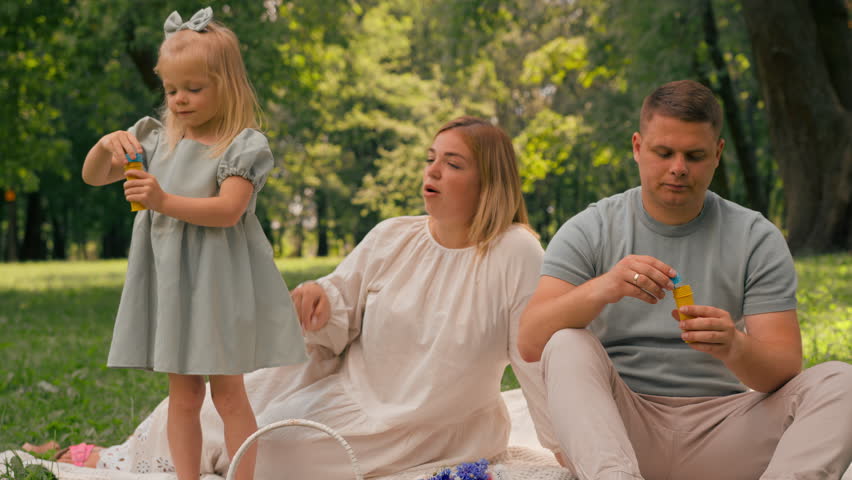 happy family relaxing outdoors in the park dad and daughter blowing soap bubbles Fun carefree childhood family weekend