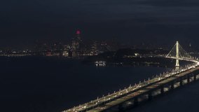 Establishing Aerial View Shot of San Francisco CA, California, United States, America at night evening, clear, San Francisco Skyline, busy freeway, circling right, Bay Bridge, Oakland Bridge