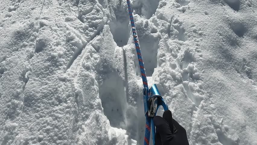 A view of the hands of a climber in black gloves, holding onto a jumar and climbing up the mountain on a rope. A climber climbs the Delaunay Pass. Climbing Belukha. Beautiful nature of Altai, Russia.