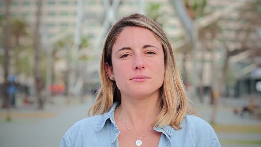 Individual close up portrait of serious young adult woman standing outside with pensive expression. Headshot of pretty confident female looking thoughtful at camera. Real formal lady staring front
