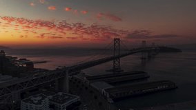 Establishing Aerial View Shot of San Francisco CA, California, United States, America, red and orange sunset, superb colors, Bay Bridge, track back towards city reveal shot p2