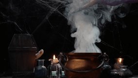 The witch's cauldron smokes on the table. Witch brews a potion. Video 4k